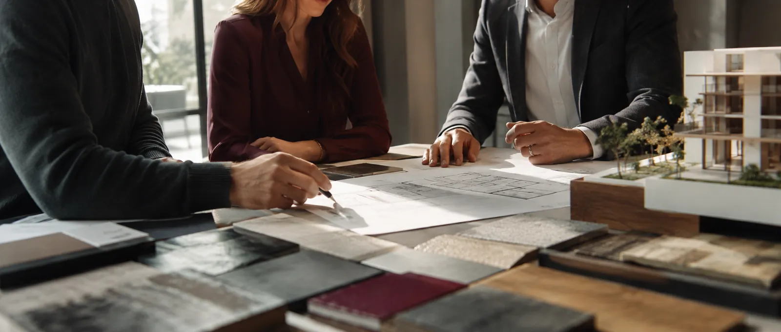 A sales conversation around architectural plans, materials and a scale model